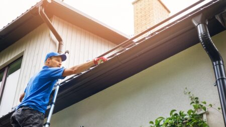 Man on ladder perfoming Professional Gutter Cleaning